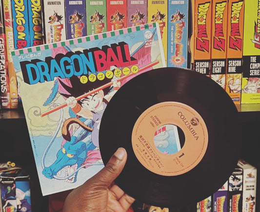 person holding popular 80s anime Dragon Ball vinyl record in front of book case