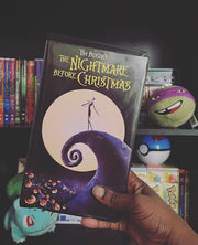 Photo of someone holding a VHS tape copy of the popular 90's Disney movie The Nightmare Before Christmas in front of a shelf